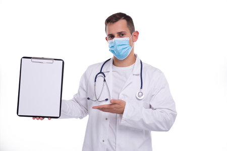 Doctor Man Showing Blank Clipboard Pointing at it Wearing Medical Mask Isolated. Advertisment, Office, Commercial Conceptの写真素材