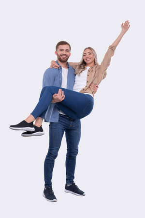 Man Holding Girl in his Arms. Couple Standing Isolated. Lovely Couple Looking to the Camera Girl is Happy Holding Hand Up. Cute Couple, Family, Friends, Lovers Concept. Coupleの写真素材