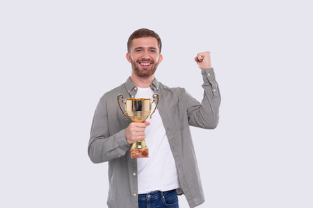 Man Very Happy and Excited, Raising arms, Celebrating a Victory or Success Holding Trophy. Winner Sign. an Isolated with Trophy in Hands. Looking to Cameraの写真素材