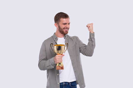 Man Very Happy and Excited, Raising arms, Celebrating a Victory or Success Holding Trophy. Winner Sign. an Isolated with Trophy in Hands. Trophyの写真素材