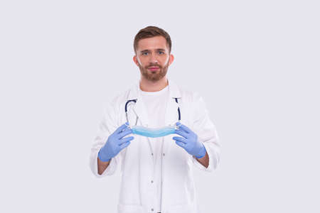 Male Doctor Puts on Medical Mask Wearing Gloves. Doctor Medical Workwear. Medical Concept. Doctor Holding Medical Maskの写真素材