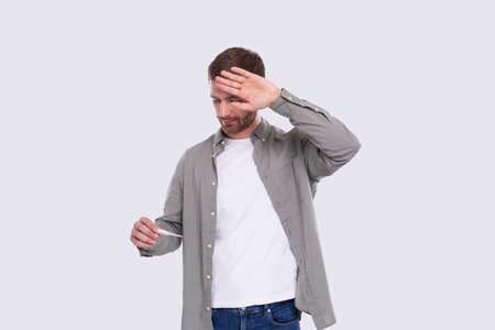 Man Looking at Thermometer Feeling Sick. Checking Themperature. Isolatedの写真素材