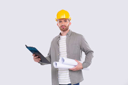 Construction Worker Holding House Plan and Clipboard in Hands. Architect Holding Blueprints. Yellow Hard Helmet. Worker Serious Faceの写真素材