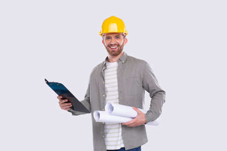 Construction Worker Holding House Plan and Clipboard in Hands. Architect Holding Blueprints. Yellow Hard Helmet. Worker Smillingの写真素材
