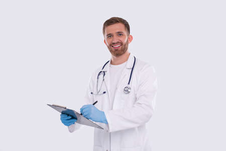 Man Doctor Writing in Clipboard Watching in Camera Isolated. Doctor with Clipboard. Commecial, Shopping, Advertisment Concept Isolatedの写真素材