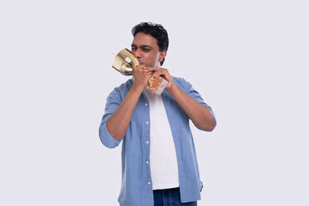 Indian Man Very Happy and Excited, Raising arms, Celebrating a Victory or Success Holding Trophy. Winner Sign. an Isolated with Trophy in Hands. Kissing trophyの写真素材
