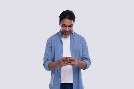 Indian Man Standing Using Phone Over Exceeded Isolated. Man Texting on Phone. Technologyの写真素材