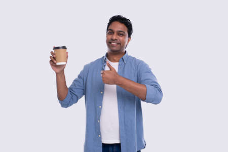Indian Man Holding Coffee To Go Cup Showing Thumb Up. Indian Man With Coffee Take Away Cup in Hand. Isolatedの写真素材