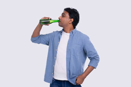 Indian Man Drinking Beer from Glass Beer Bottle. Indian Man with Drink in Hands Isolatedの写真素材