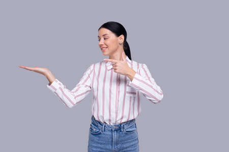 Girl Holding Hand to Side Pointing at Hand Isolatedの写真素材