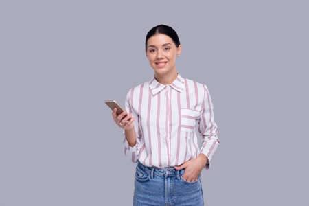 Girl Holding Phone Standing Looking ot Camera Isolated. Commecial, Shopping, Advertisment Conceptの写真素材