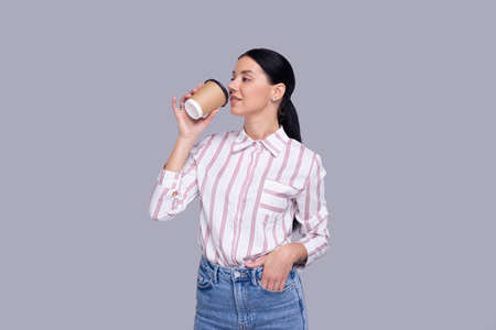Girl Drinking Coffee from Take Away Cup. Girl With To Go Coffee Cup in Hands. Isolatedの写真素材