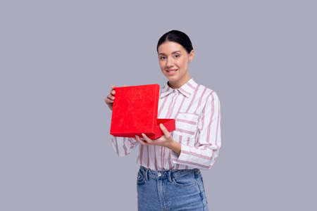 Girl Holding Present Watching to Camera. Girl Holding Gift. Surprise. Isolatedの写真素材