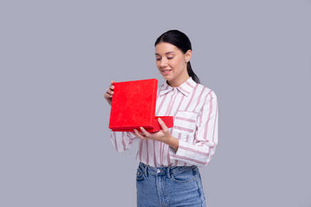 Girl Holding Present Watching Whats inside. Girl Holding Gift. Surprise. Isolatedの写真素材