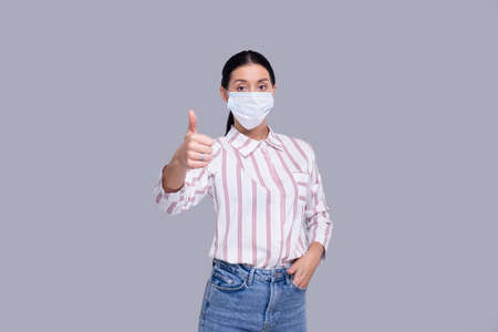Girl Wearing Medical Mask Showing Thumb Up Isolated. Woman In Office look with Medical Mask. Health, Virus, Medical Concept Isolatedの写真素材