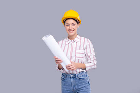 Girl Construction Worker Holding House Plan in Hands Watching in Camera. Girl Architect Holding Blueprints. Yellow Hard Helmet. Workerの写真素材