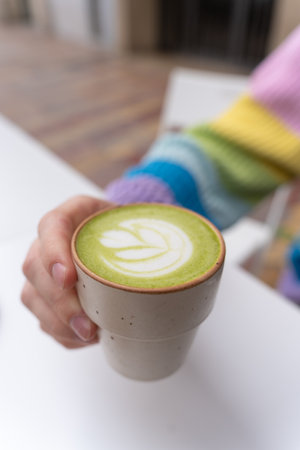 Man Hands Holding Macha Latte Cup with Wooden Plate in Caffeの写真素材