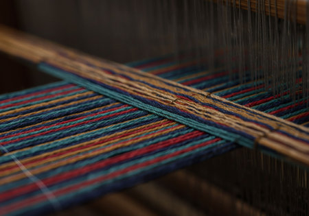 Macro shot of traditional Indonesian loom with colorful hand-spun threads under soft daylight, showing intricate textures and artisan craftsmanship.の素材
