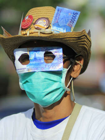 Yogyakarta, Indonesia, 9 Dec 2014. Anti-corruption activists cover their eyes with a piece of money as a form of protest against rampant corruptionのeditorial素材