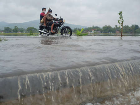 Klaten, Indonesia, Feb 5, 2021. Motorized vehicles passing through flood currents that overflowed from the river due to heavy rainfall.のeditorial素材