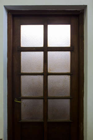 The door to enter and exit a room made of wood is combined with frosted glass so as not to limit the lighting on both sides of the roomの写真素材