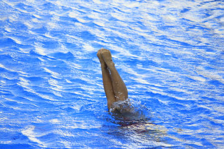 A swimmer's feet are above the surface of the water when half of his body and head are submergedの写真素材