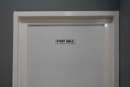 The white door with the text "Staff Only" tells that access to the room behind it is limited to internal only.の写真素材