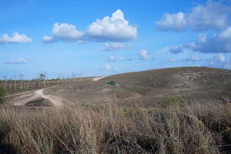 Civilian cars cross alternative routes in barren hilly areas, bordering Southwest Sumba and West Sumba, Indonesia.の写真素材
