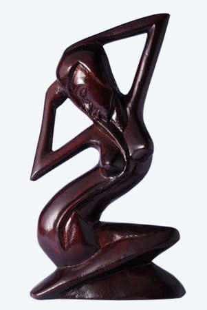 A statue of a dark female figure posing while sitting made of woodの写真素材