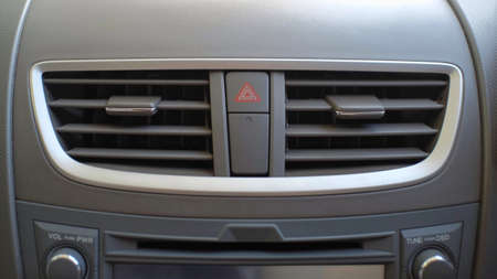 Air conditioning on the dashboard of the car flanks the red triangle sign which functions to turn on the hazard lightsの写真素材