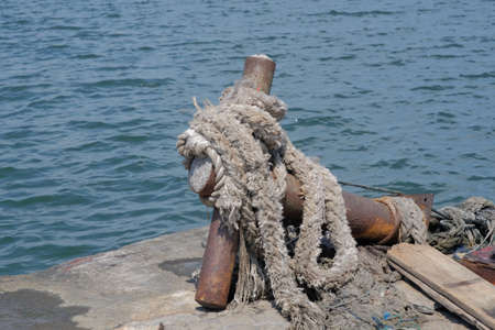 The large mooring rope was wrapped around an unused iron rodの写真素材