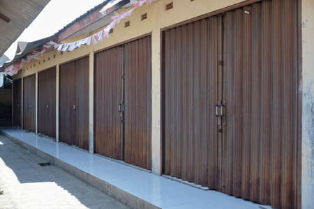 A row of shophouses with a folding gate model that is tightly closed in a market that is no longer operationalの写真素材