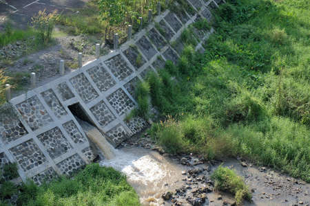 The waterfall is quite swift coming out of the small irrigation channel into the river flowing the bigger river.の写真素材
