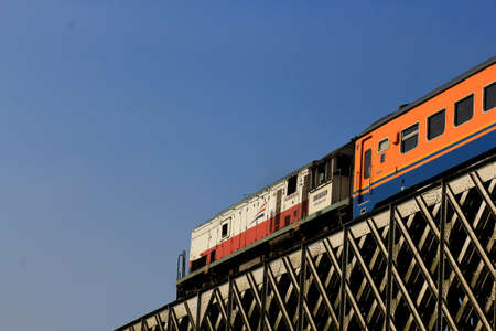 Indonesia, June 16, 2014: The Indonesian Railway passes through a steel bridge under a blue sky. Trains are one of the favorite means of transportation of citizens.のeditorial素材