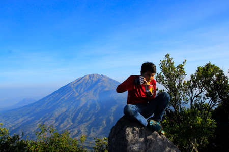 Boyolali, Central Java, Indonesia, Oct 25, 2014: A climber enjoy breakfast noodles background view Merbabu, in the path of ascent to Mount Merapi.のeditorial素材