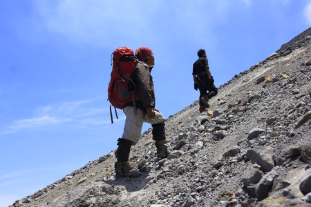 Yogyakarta, Indonesia, Oct 25, 2014. Two climbers take time off on a stretch of sand and rock on their way to the top of Mount Merapi.のeditorial素材