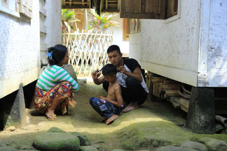 Tasikmalaya, Indonesia, July 24, 2015. Parents are trimming their children's hair with simple scissors and combs around the house.のeditorial素材