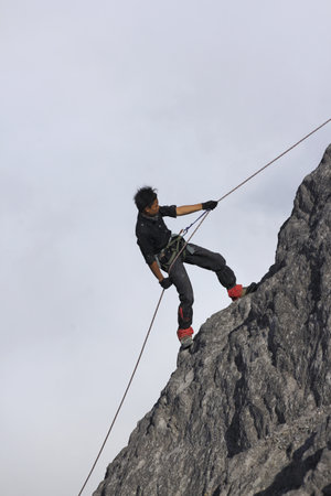 Yogyakarta, Indonesia, Oct 25, 2014. A man was climbing a ridge of hills using a rope at Mount Merapi.のeditorial素材