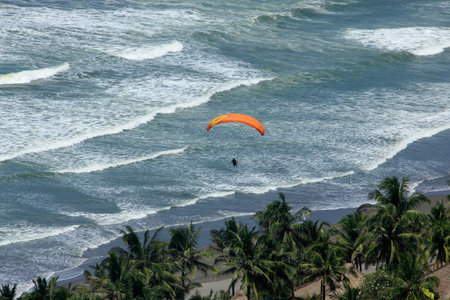 Yogyakarta, Indonesia, Feb 18, 2018. Paragliding athlete preparing landing on Parangtritis beach under the sunny weather in Jogja Air Show.の写真素材