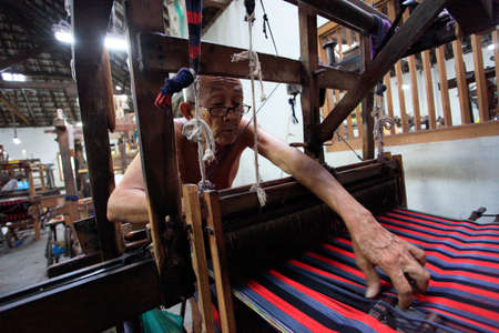 Yogyakarta, Indonesia, March 23, 2016. The oldest worker carefully checks the woven fabric in the Lurik Kurnia weaving factory.のeditorial素材