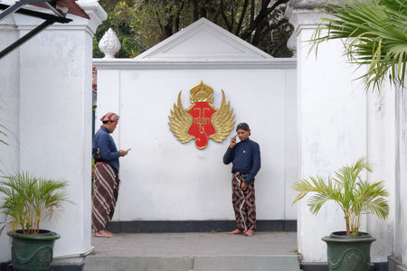 Yogyakarta, Indonesia, July 28, 2019. Two courtiers of the Yogyakarta Palace are busy with mobile communication devices.のeditorial素材