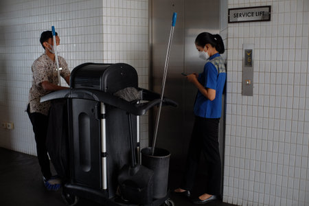 Yogyakarta, Indonesia, Oct 1, 2021. Hotel staff carrying a cleaning cart stands near the elevator door.のeditorial素材