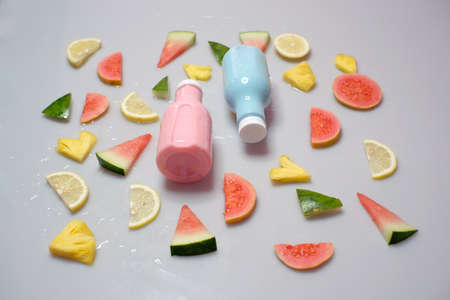 Slices of guava, lemon, watermelon, pineapple, arranged around two bottles of freshness drink made from fruit.の写真素材