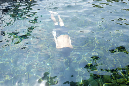 A person swimming or diving under the clear surface of the pool water.