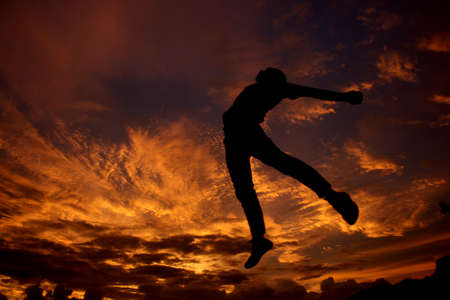 Yogyakarta, Indonesia, Jan 16, 2009. Silhouettes of people jumping high representing freedom against the backdrop of a burning twilight sky.の写真素材