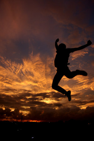 Yogyakarta, Indonesia, Jan 16, 2009. Silhouettes of people jumping high representing freedom against the backdrop of a burning twilight sky.の写真素材