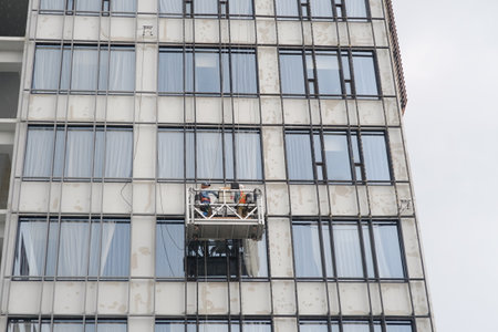 Yogyakarta, Indonesia, Jan 27, 2019. Building maintenance workers work at the height of a hotel, using standard safety equipment.のeditorial素材