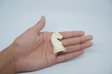 Someone's hand was holding a Knight chess piece. In the game of chess, horses or Knight have a unique and deadly move, namely the L move.の写真素材