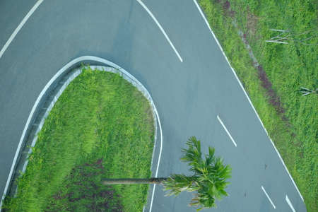 An empty asphalt road cuts through a green grass field.の写真素材
