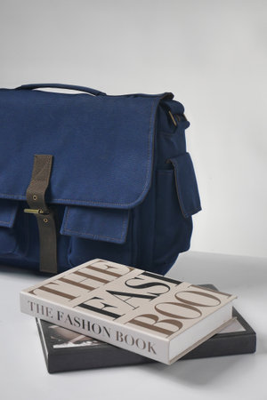 Books on fashion topics and a blue sling bag isolated on whiteの写真素材
